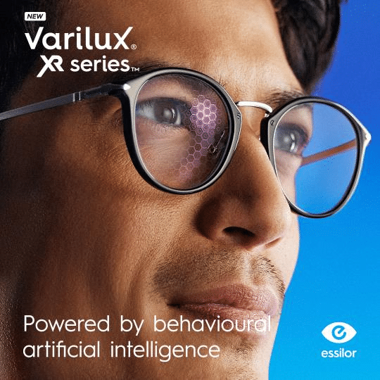 Man wearing glasses with hexagonal pattern reflected in lenses; text reads “Varilux XR series, powered by behavioural artificial intelligence,” highlighting Essilor’s commitment to quality lens innovation, with the Essilor logo.
