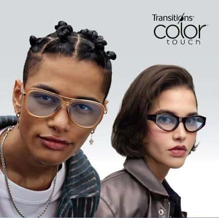 Two people wearing eyeglasses with tinted lenses—featuring high-quality Essilor lenses, one in gold aviator frames and the other in black cat-eye frames—pose in front of a gray background with the “Transitions color touch” logo.